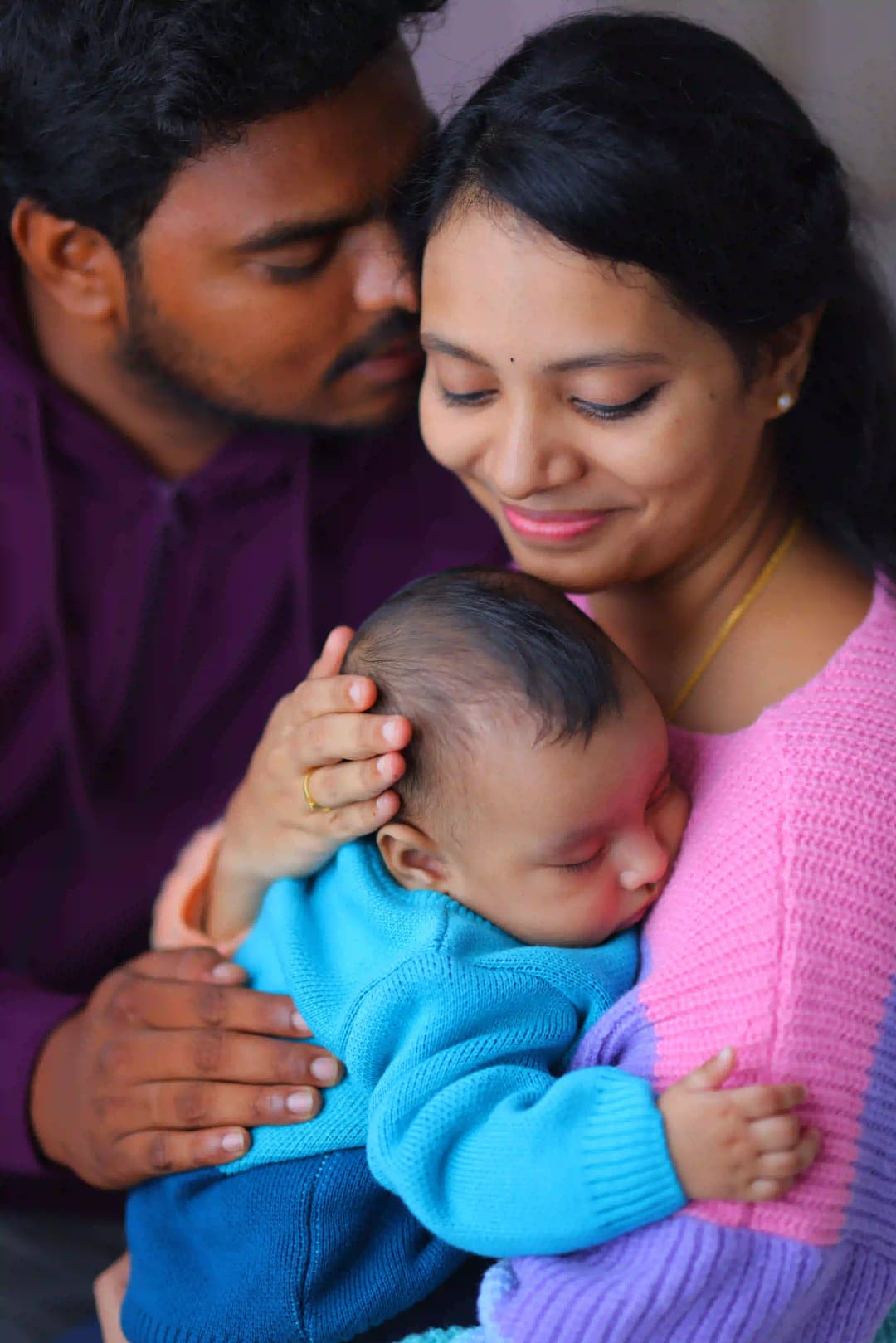 Loving parents holding their newborn baby as he peacefully sleeps in their arms, capturing a tender family moment.