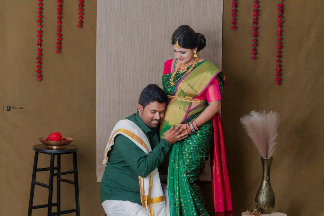 Expecting parents sharing a tender moment with the mother showing her baby bump, in a traditional outfit.