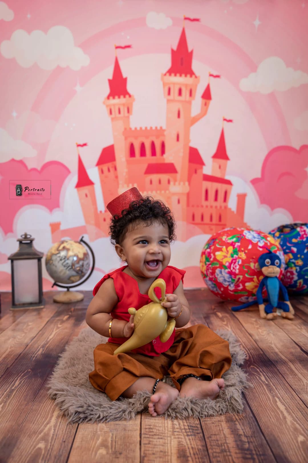 Baby dressed in an Aladdin-inspired outfit with a red vest, sitting with a magic lamp, and a castle backdrop for a fun themed photo shoot.